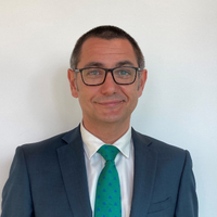 Persona con traje y corbata verde sonriendo.