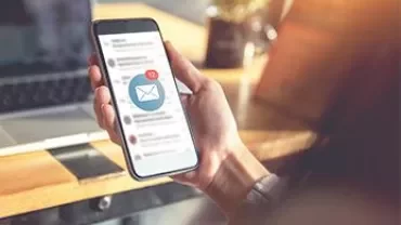 Mano sosteniendo un teléfono con notificación de correo electrónico.