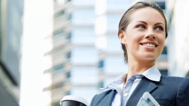 Persona sonriendo con traje, sosteniendo una taza y un periódico.