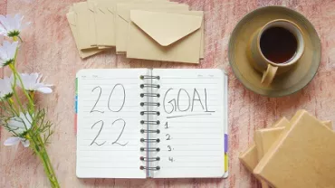 Agenda abierta con hojas en blanco junto a una taza de café.