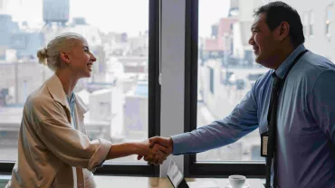 Dos personas dándose la mano con una vista de la ciudad al fondo.