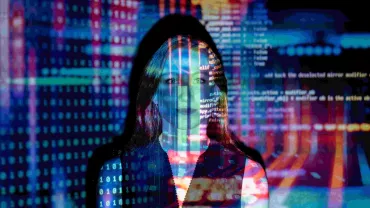 Persona en pantalla proyectada con código y gráficos digitales.