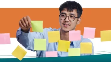 Persona organizando notas adhesivas de colores en una superficie transparente.