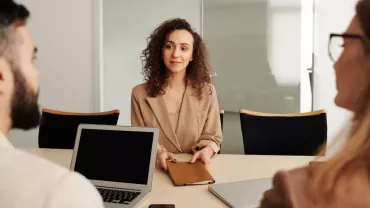 Persona en una reunión de negocios con un portátil en una mesa.