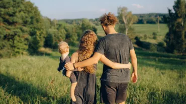 Tres personas caminando por un campo verde.