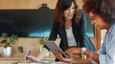 Dos mujeres mirando una tablet y sonriendo