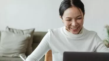 Mujer sonriente mira la pantalla del ordenador