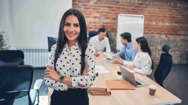 Mujer profesional en una oficina con su equipo por detrás.