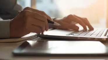  Imagen de unas manos y un ordenador como si estuviese trabajando o tecleando.
