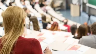 Jóvenes en un entorno de formación, comparando opciones de carrera, con una pizarra o portátil con información sobre FP y universidad