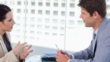 Dos personas hablando en una sala de juntas moderna.