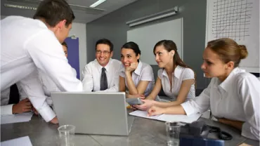 Reunión de equipo con personas interactuando alrededor de una mesa.