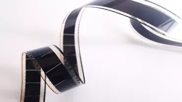 Cinta de película de cine enrollada sobre fondo blanco.