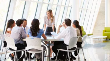 Grupo de personas en una reunión alrededor de una mesa en una oficina moderna.