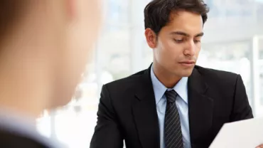 Persona en traje revisando un documento en una oficina.