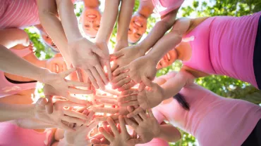 Grupo de personas uniendo manos en círculo al aire libre.