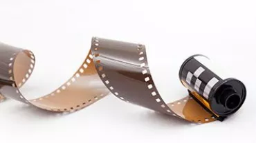 Carrete de película fotográfica desenrollado sobre fondo blanco.