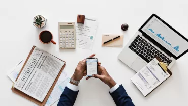 Mesa de trabajo con portátil, móvil y documentos.