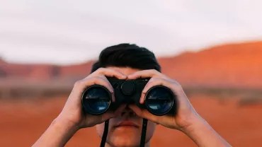 Persona observando con binoculares en un paisaje desértico.