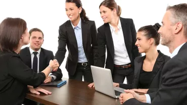 Grupo de personas en reunión laboral, estrechando manos.