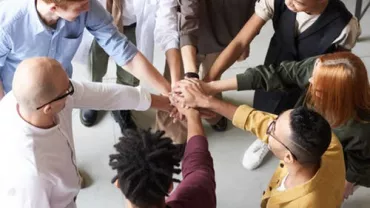 Grupo de personas uniendo manos en un círculo.