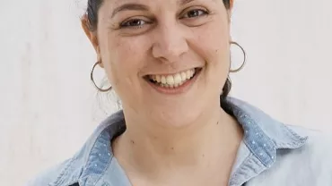 Persona sonriente con camisa de mezclilla.