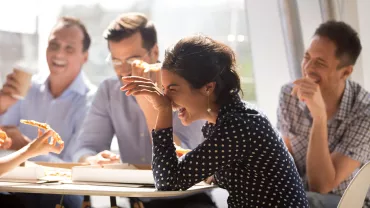 Grupo de personas riendo mientras comen pizza.