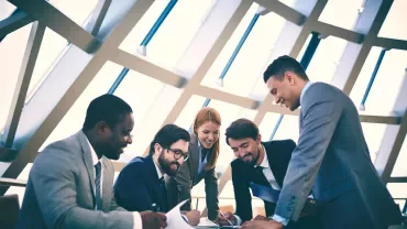 Personas en una reunión de trabajo, sonriendo y discutiendo.