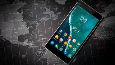 Teléfono móvil en pantalla principal sobre mapa mundial.