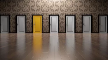 Fila de puertas grises con una puerta amarilla resaltando.