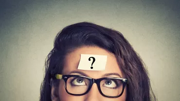 Persona con gafas y nota adhesiva con signo de interrogación en la frente.