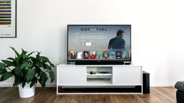 Televisor con película y catálogo de videos en una sala moderna.