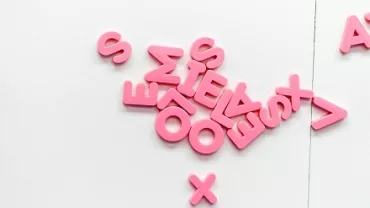 Letras rosadas dispersas sobre una superficie blanca.