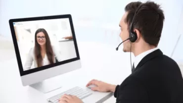 Persona con auriculares en videollamada en computadora.