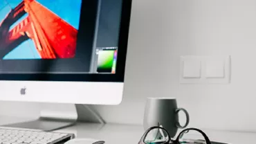Escritorio con computadora, taza y gafas.