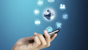 Mano sosteniendo un teléfono con íconos digitales alrededor.