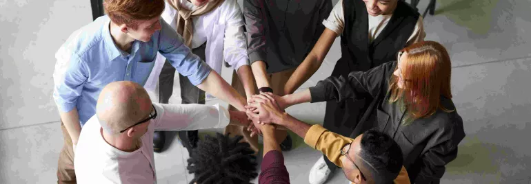 Grupo de personas uniendo manos en equipo.