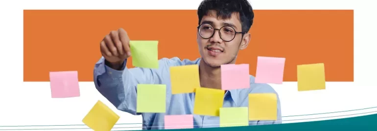 Persona organizando notas adhesivas de colores en una superficie transparente.
