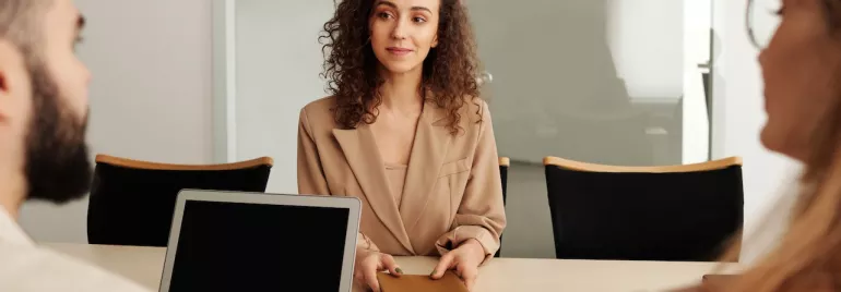 Persona en una reunión de negocios con un portátil en una mesa.