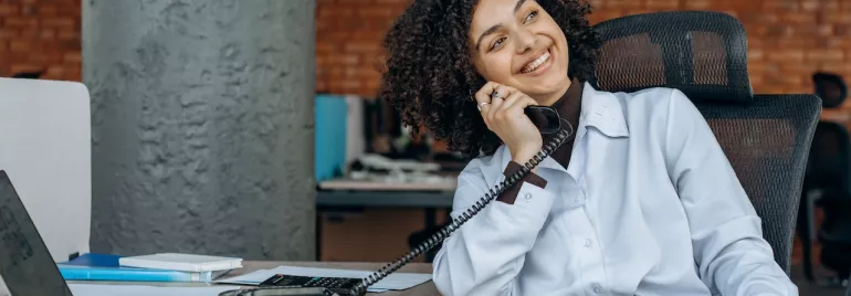 Persona sonriente hablando por teléfono en la oficina.