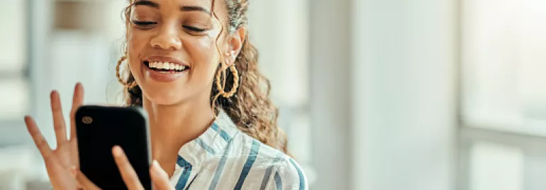 Persona sonriendo mientras usa un teléfono móvil.