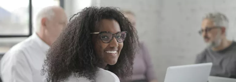 Persona sonriendo en una reunión con ordenador portátil.