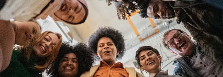Grupo de personas formando un círculo y sonriendo hacia la cámara.