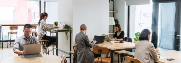 Personas trabajando en una cafetería luminosa.
