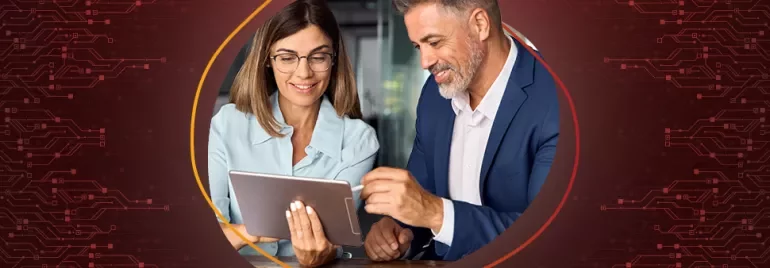 Una mujer vestida formal sostiene una tableta mientras un hombre con traje utiliza un lápiz digital para firmar un documento en la pantalla de la tableta. 