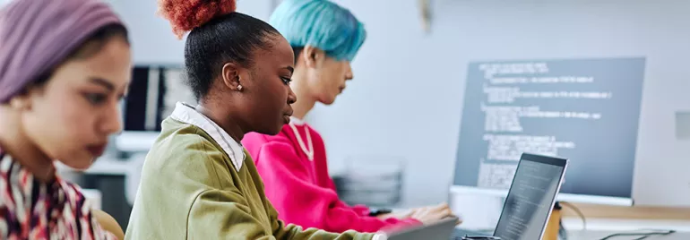 Personas trabajando en computadoras portátiles en una oficina.