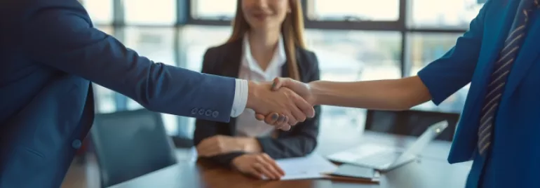 Personas dándose la mano en una oficina moderna con fondo de ventana.