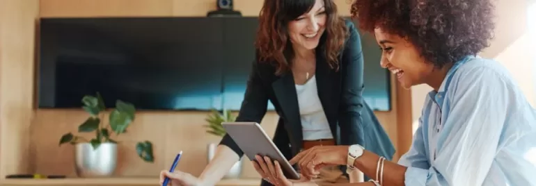 Dos mujeres mirando una tablet y sonriendo