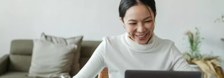 Mujer sonriente mira la pantalla del ordenador