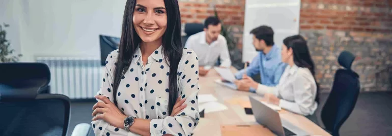 Mujer profesional en una oficina con su equipo por detrás.